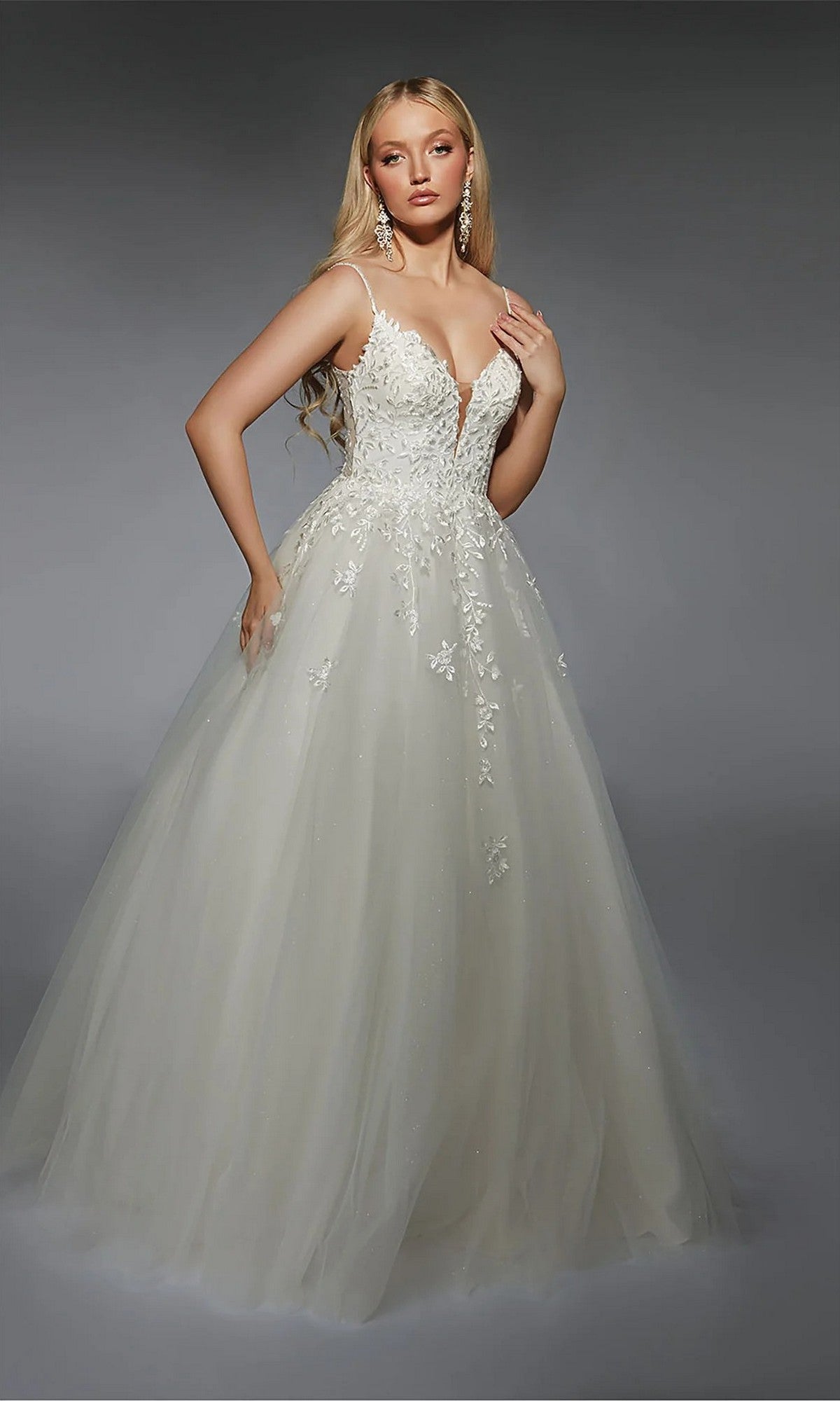 A woman in the Alyce 7127 long ivory dress, featuring a fitted floral-embroidered bodice and a full tulle skirt, stands against a gray background.